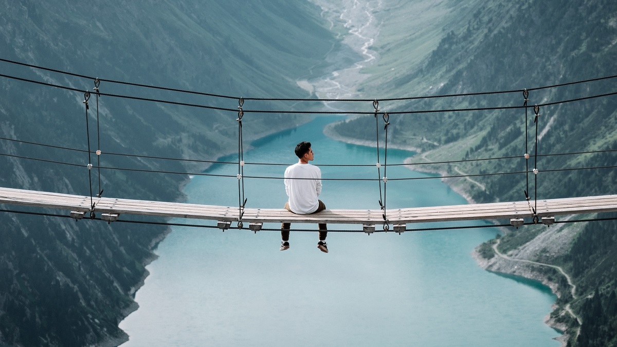 A lone man sits on a bridge.